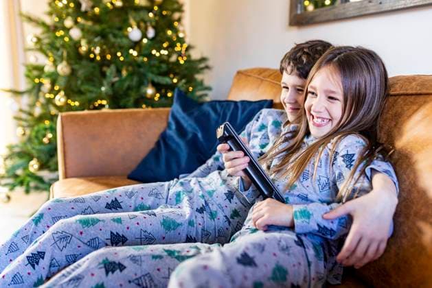 IMAGO Creative, Weihnachten, Tradition: Weihnachtsfilme sehen Happy girl watching TV with brother at home at Christmas time model released, Symbolfoto property released, WPEF07416