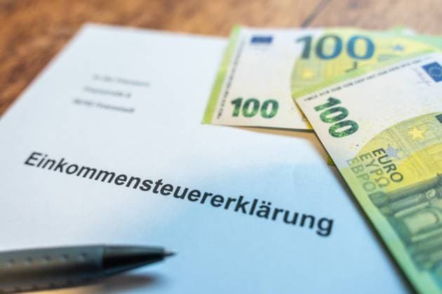 Augsburg, Bavaria, Germany - 23 June 2023: Euro banknotes on a letter with inscription: Income tax return *** Euro Geldscheine auf einem Brief mit der Aufschrift: Einkommenssteuererklärung