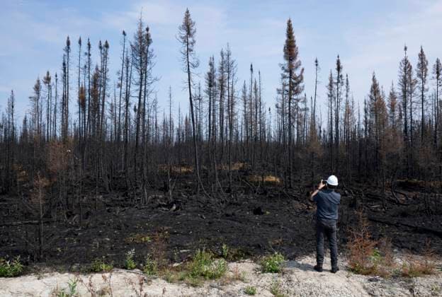 July 5, 2023, Lebel-sur-Quevillon, PQ, Canada: A reporters takes a photo of forests damaged by fire during a tour near Lebel-sur-Quevillon, Que., Wednesday, July 5, 2023. Lebel-sur-Quevillon Canada  - ZUMAc35_ 20230705_zaf_c35_023 Copyright: xAdrianxWyldx