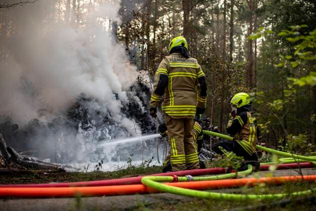 Feuerwehr löscht Holzstapelbrand bei Kleinmachnow, Bei Kleinmachnow (Potsdam-Mittelmark) ist am Sonntag Abend ein großer Holzstapel in Brand geraten und hat teilweise auf den Wald übergegriffen. Die brennende Fläche wurde von den eingesetzten Kräften der Feuerwehr Kleinmachnow schnell gelöscht. Kleinmachnow Brandenburg Deutschland *** Fire department extinguishes wood pile fire near Kleinmachnow, Near Kleinmachnow Potsdam Mittelmark is on Sunday evening a large wood pile on fire and has partially spread to the forest The burning area was quickly extinguished by the deployed forces of the fire department Kleinmachnow Brandenburg Germany