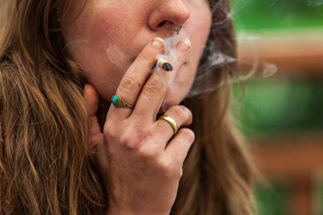 Pot blunt smoked by woman outdoor in nature Closeup cropped shot of caucasian womans face with hand rolled marijuana joint held by her ring covered fingers Pot smoke escapes from her lips ,model released, Symbolfoto Copyright: xZoonar.com EmmanuelxLavignex 14978956 ,model released, Symbolfoto ,property released