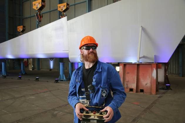Vor-Ort-Pressetermin am Dienstag (11.07.2023) in der Hanse- und Universitätsstadt Rostock Ortsteil Warnemünde auf der örtlichen Neptunwerft zur Kiellegung für das Forschungsschiff Meteor IV mit der Staatssekretärin im Bundesministerium für Bildung und Forschung Judith Pirscher. Die Werft wurde 1850 gegründet. Sie gehört seit 1997 zur Meyer Neptun Gruppe. Die baut an der Warnow insbesondere Flusskreuzfahrtschiffe und Spezialschiffe. Nun wurde mit der Montage der Meteor ein weiterer Schiffsneubau gestartet. Dieser wird künftig eine Länge von etwa 125 Meter und eine Vermessung von ca.10.000 BRZ haben und soll 2026 abgeliefert werden. Hier im Bild der Kranführer Tobias Dachner vor dem Absenken der Sektion auf die Pallungen