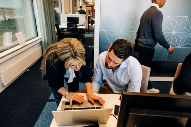Businesswoman assisting male colleague over laptop in coworking office Sweden, Stockholm, model released, property released Copyright: xMaskotx , MA102014 MA102014