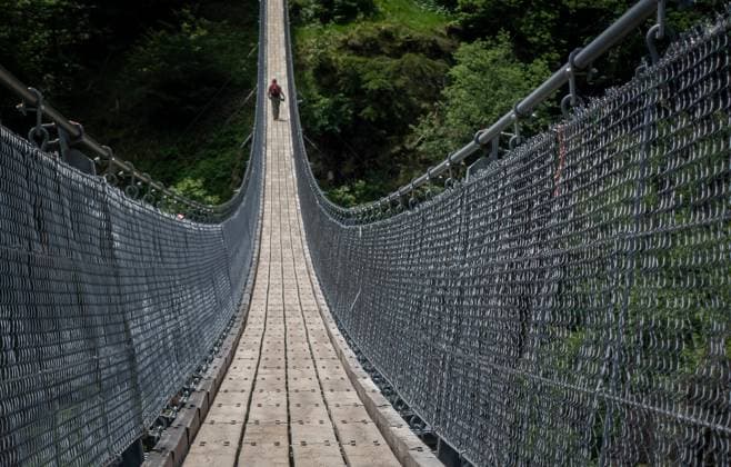 Bellinzona: Hängebrücke auf der Wanderstrecke. Auf einer Länge von 270 Metern überspannt die Tibetische Hängebrücke Carasc ein Tal bei Bellinzona im südschweizer Kanton Tessin. Die Hängebrücke in einem dichten Waldgebiet, die bis zu 130 Meter über dem Tal schwebt, gehört zu einem acht Kilometer langen Wanderweg zwischen den Gemeinden Monte Carasso und Sementina. Das 2015 fertiggestellte Bauwerk kostete mehr als 1,6 Millionen CHF. Der Name Tibetische Brücke resultiert aus der Bauweise. Bellinzona Tessin Schweiz *** Bellinzona Suspension Bridge on the Hiking Trail Over a length of 270 meters, the Tibetan Suspension Bridge Carasc spans a valley near Bellinzona in the southern Swiss canton of Ticino The suspension bridge in a de