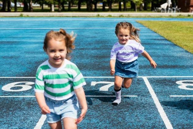 IMAGO Creative: Sommer, Sommertage im Stadtpark MR_ID14992_14133_SofiaVazquezEsmerode.jpg, MR_ID14992_14134_AdrianaMoralesPineiro.jpg Cute little girls in casual clothes smiling and running on stadium track during outdoor sports training at playground of city park, Model released AidaMartinez_ID14992_458079_011 Copyright: xAidaxMartinezx RECORD DATE NOT STATED MR