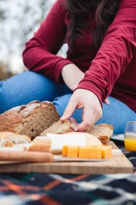 MR_ID14903_13940_CarlaNahuelhual.jpg From below crop person taking piece of bread placed on cheeseboard on fabric while having picnic in countryside, Model released Padnob_ID14903_455356_011 Copyright: xPadnobx MR