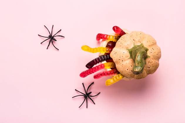 Halloween decorations. Pumpkin with treat of marmalade worms and spiders on pink background Halloween decorations. Pumpkin with treat of marmalade worms and spiders on pink background. Copyright: xZoonar.com ElenaxNazarovax 20456456