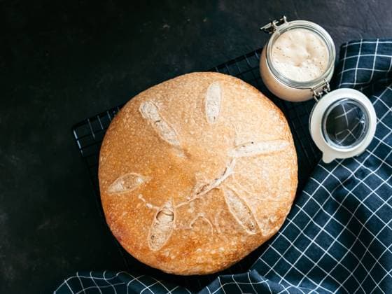 Wheat round sourdough bread, copy space, top view Wheat round sourdough bread and sourdoug starter in glass jar. Top view of delicious homemade sourdough bread on black background with copy space. Home made sourdough bread making concept. Copyright: xZoonar.com OlgaxSergeevax 20468230
