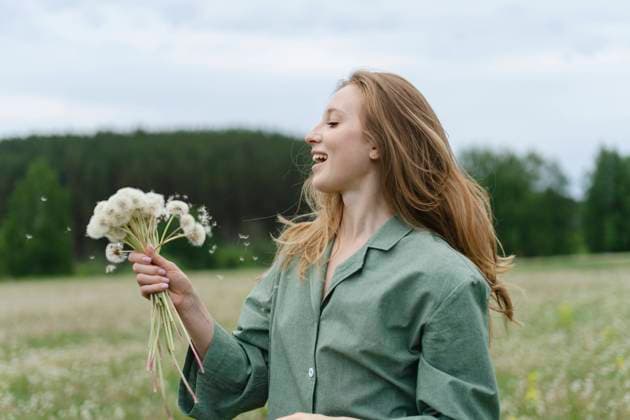 Creative Highlights Symbolbilder Smiling young woman holding dandelions on field model released, Symbolfoto, SEAF01990