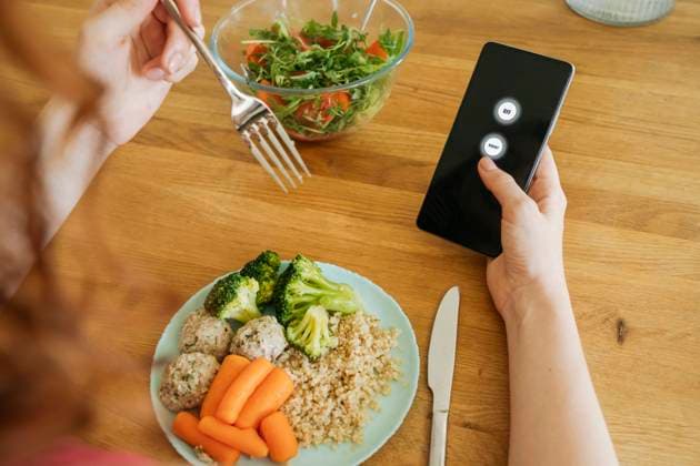 Young woman with food and smart phone sitting at dining table model released, Symbolfoto property released, OSF01773