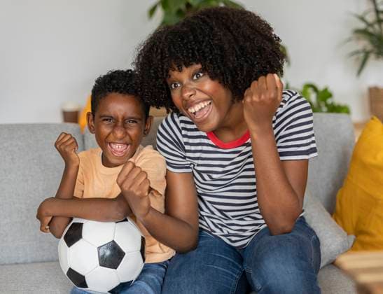 Happy mother and son cheering and sitting on sofa at home model released, Symbolfoto property released, JCCMF10574
