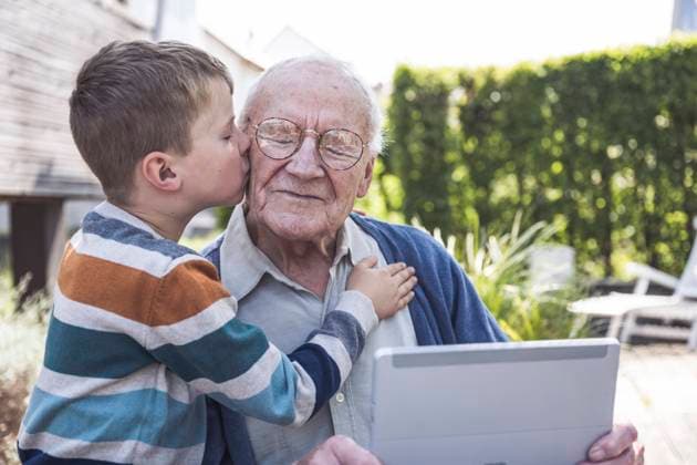 IMAGO Creative, Gesellschaft, Immer mehr Menschen haben Angst vor der Zukunft Boy kissing and embracing grandfather holding tablet PC model released, Symbolfoto property released, UUF29027