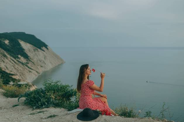 Creative Highlights Symbolbilder young woman sits in summer mountain, sea with a flower in her hand Anapa, Krasnodar Krai, Russia R_ONIB220815-1028243-01 ,model released, Symbolfoto
