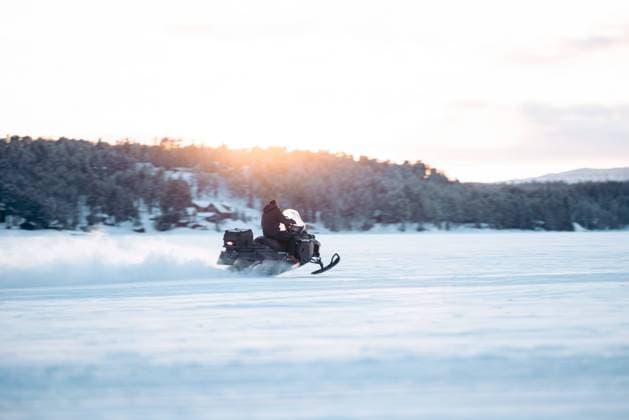 Unrecognizable person in warm clothes riding snowmobile on snowy field near forest under sky Model Released EricPanades_ID15461_471191_075 Copyright: xEricxPanadesx RECORD DATE NOT STATED