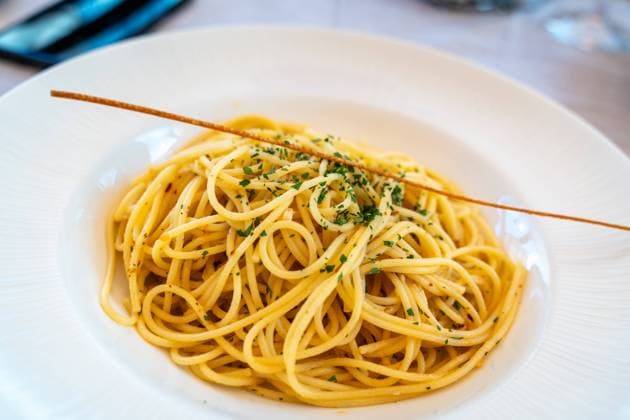 Riva, Lake Garda, Italy - 7 August 2023: Original Italian spaghetti algio e olio in a plate served in a restaurant *** Originale italienische Spaghetti Algio e Olio in einem Teller serviert in einem Restaurant