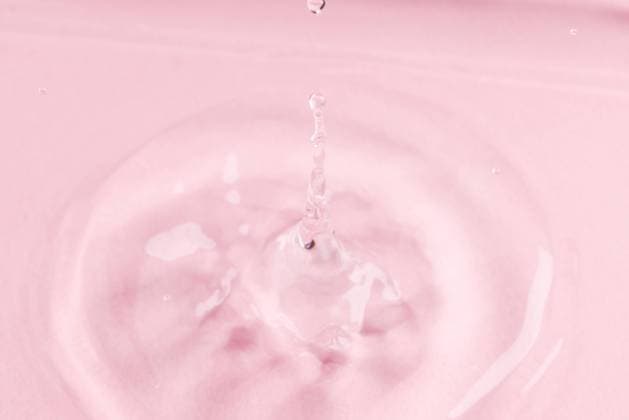 Close up of water drop falling into water with ripples and copy space on pink background. Water, liquid and colour concept. Copyright: xx 4132840