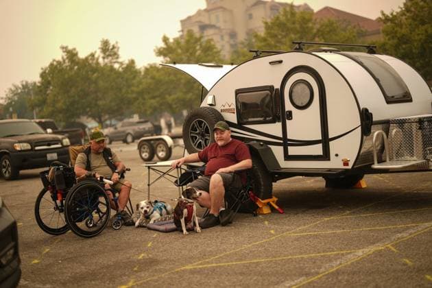 August 19, 2023, KELOWNA, BC, CANADA: Veteran Rob Pullen, left, and Warren Pullen, who were evacuated from their home on Thursday due to wildfires, sit with their dogs outside their trailer in the parking lot at an evacuation centre, in Kelowna, B.C., Saturday, Aug. 19, 2023. KELOWNA CANADA - ZUMAc35_ 20230819_zaf_c35_018 Copyright: xDarrylxDyckx