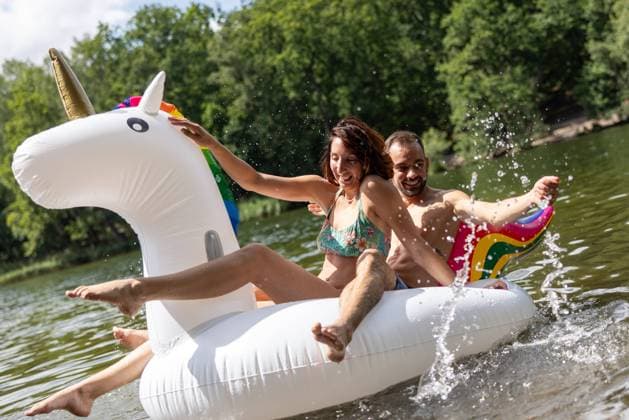 CREATIVE - Paar am See in Berlin Berlin, Deutschland - 25. Juli 2023: (CREATIVE) Ein Mann und eine Frau (Models) genießen auf einem aufgeblasenen Einhorn einen Sommertag an der Krummen Lanke, einem See in Berlin. Berlin