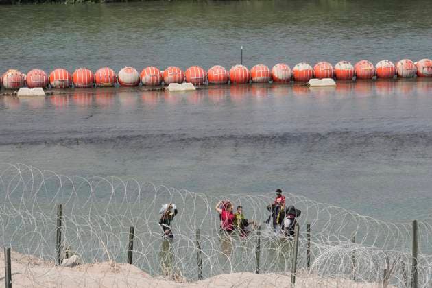 USA, Migranten aus Mittelamerika am Rio Grande in Eagle Pass, Texas August 21, 2023, Eagle Pass, TX, United States: A group of migrants look for an opening in the concertina wire barrier south of Eagle Pass where a 1000-foot string of buoys has been placed in the river to deter crossing the Rio Grande River into Texas. The migrants later found an opening and crossed into the United States as several U.S. governors were touring overhead by helicopter. Eagle Pass United States - ZUMAd150 20230821_znp_d150_044 Copyright: xBobxDaemmrichx