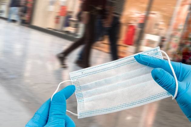 Hand holding mask and wearing for protection from virus or air pollution of dust on supermarket stairs background .Hand holding mask and wearing for protection from virus or air pollution on supermarket stairs background Copyright: xCHASSENETx xBSIPx 016091_015 Bsip_016091_015 model release