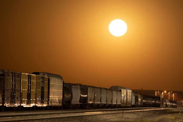 Moon rise as an orange glowing sphere over freight train Lordsburg, New Mexico, United States R_MALI230812-1230954-01