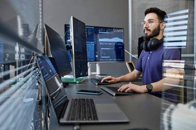 Young computer programmer with wireless headphones working on desktop PC model released, Symbolfoto property released, KPEF00133