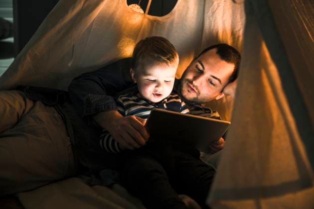Father and son sharing a tablet in a dark tent at home model released, Symbolfoto property released, UUF16881