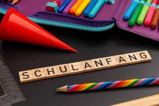 Bavaria, Germany - 24 August 2023: Back to school text made of wooden cubes in front of a school pencil case on a chalkboard. Start of school for children *** Schulanfang Text aus Holzwürfeln vor einem Schulmäppchen auf einer Kreidetafel. Beginn der Schule für Kinder