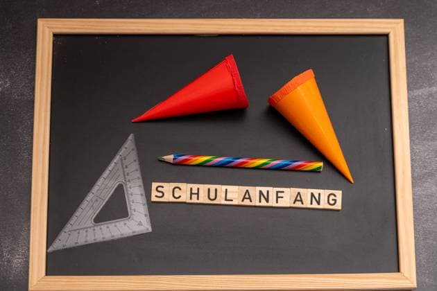 Bavaria, Germany - 24 August 2023: Wooden letters with the word: start of school. School bags on a chalkboard. Start of school symbol image *** Holzbuchstaben mit dem Wort: Schulanfang. Schultüten auf einer Kreidetafel. Beginn der Schule Symbolbild