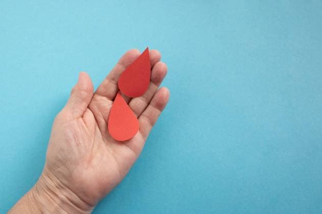 The concept of the World Blood Donor and Hemophilia Day. Two red paper drops of blood in the hand on a blue background The concept of the World Blood Donor and Hemophilia Day. Two red paper drops of blood in the hand on a blue background. Copyright: xZoonar.com LubovxKlepikovskayax 18582342