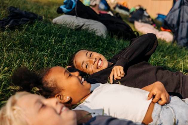 Happy girl enjoying with friends while lying down on grass at summer camp Sweden, Stockholm, model released Copyright: xMaskotx , MA103407 MA103407