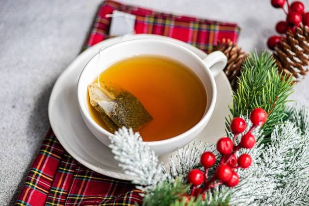 High angle of Christmas cup of tea placed on red napkin near holly and pine cones on gray table Model Released AnnaBogush_ID16539_502682_003 Copyright: xAnnaxBogushx