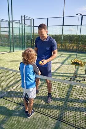 MR_ID14770_14478_MatthewJamesHudson.jpg, MR_ID14770_14477_PatrickDegroote.jpg Full body of trainer speaking with boy in activewear while standing near net during padel tennis training on court in summer day Model Released PhilippeDegroote_ID14770_448793_012 Copyright: xPhilippexDegrootex