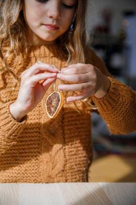 Girl tying thread on dried lemon at table model released, Symbolfoto property released, IKF01146