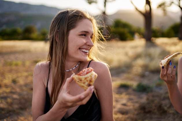 Happy woman having slice of pizza in park on weekend model released, Symbolfoto, ANNF00369