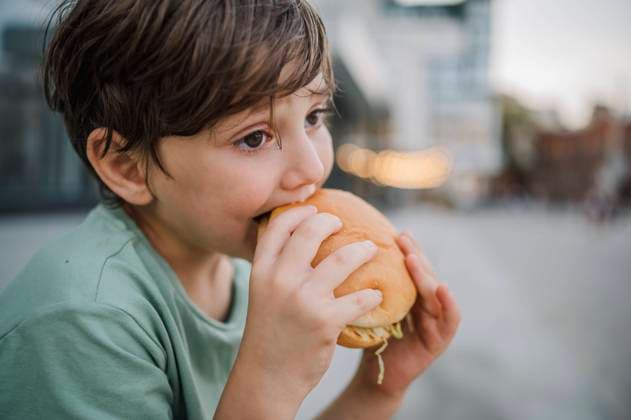 Thoughtful boy eating burger at street model released, Symbolfoto, ANAF01996