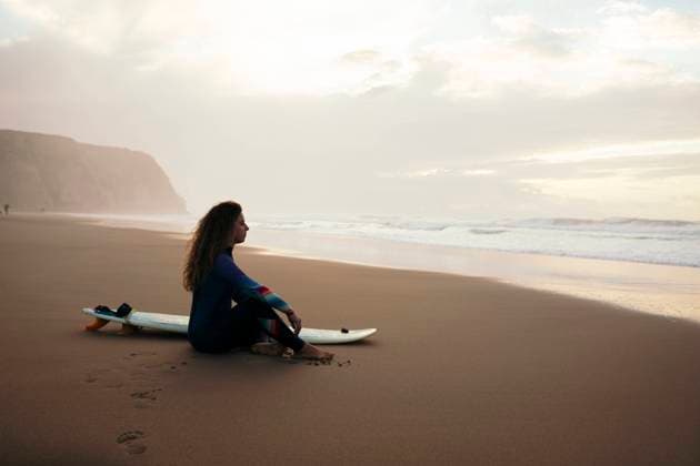 Thoughtful woman with surfboard sitting at beach model released, Symbolfoto, DCRF01769