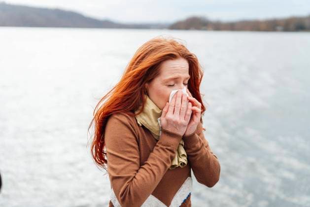 Redhead woman blowing nose in front of lake model released, Symbolfoto, KNSF09751