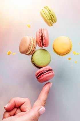 Creative Highlights Symbolbilder Finger of woman balancing macaroons in studio model released, Symbolfoto, FLMF00997