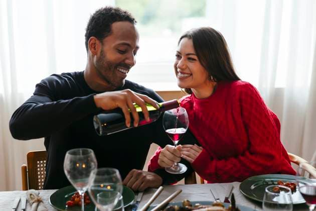Smiling man pouring red wine to woman at dinner party model released, Symbolfoto property released, EBSF03786