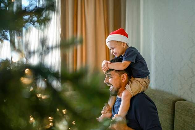 Father carrying son with Santa hat shoulders sitting on sofa model released, Symbolfoto property released, ANAF02117