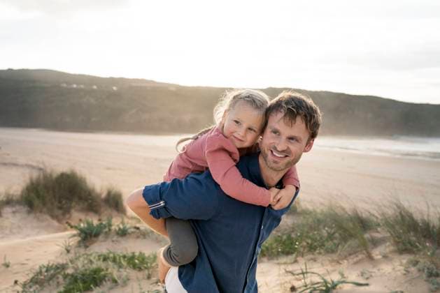 Smiling father giving piggyback ride to daughter at beach model released, Symbolfoto, SBOF04025