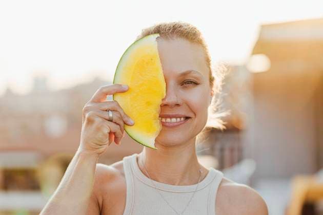 Smiling woman covering her face with yellow watermelon model released, Symbolfoto, SIF00810