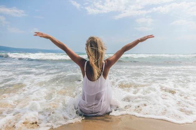 Creative Highlights Symbolbilder Woman with arms outstretched sitting at beach model released, Symbolfoto, SIF00881