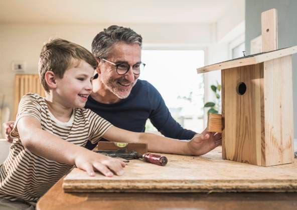 Smiling grandfather and grandson looking at birdhouse on table model released, Symbolfoto property released, UUF29990