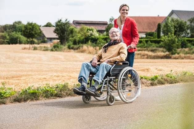 Smiling woman pushing senior man sitting in wheelchair model released, Symbolfoto, UUF30256