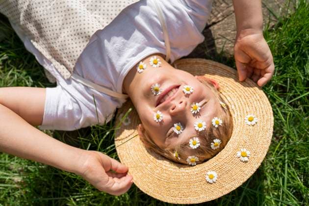 Happy boy with daisies over face relaxing on grass model released, Symbolfoto, VBUF00378