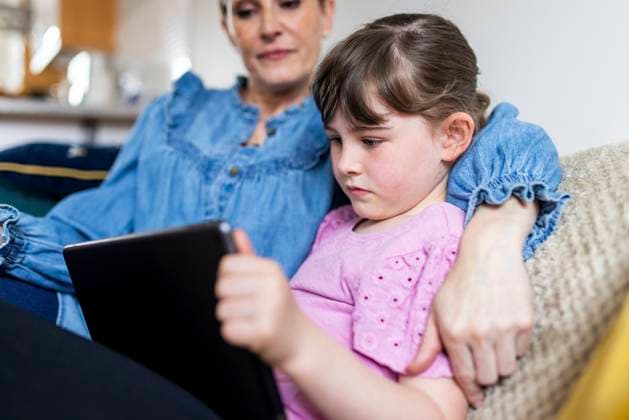 IMAGO Creative, Gesellschaft, Immer mehr Menschen haben Angst vor der Zukunft Girl using tablet PC by mother in living room model released, Symbolfoto property released, WPEF07564