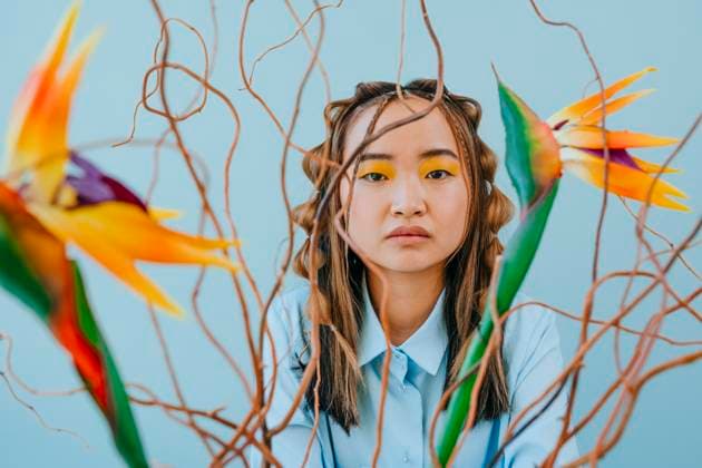 Creative Highlights Symbolbilder Young woman looking through flowers and branches in studio model released, Symbolfoto property released, YTF01154