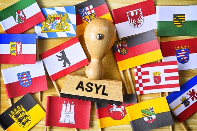 FOTOMONTAGE, Stempel mit Aufschrift Asyl inmitten Fahnen der deutschen BundeslÃ¤nder, Symbolfoto Ã¼berlastete Kommunen durch gestiegene FlÃ¼chtlingszahlen *** PHOTOMONTAGE, stamp with inscription asylum in the middle of flags of the German federal states, symbol photo overloaded municipalities by increased numbers of refugees ** NUR FUER REDAKTIONELLE ZWECKE ** EDITORIAL USE ONLY **